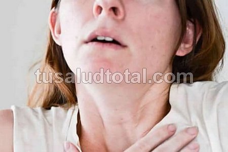 Una mujer con mano en el pecho (pitidos al respirar)