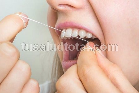 Una mujer haciendo uso de hilo dental